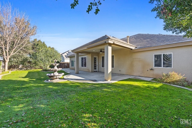 rear view of property featuring ceiling fan, a patio area, and a lawn