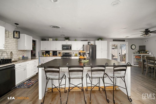 4620 Taft Hwy, Bakersfield, CA 93313 - kitchen with stainless steel appliances, tasteful backsplash, white cabinetry, and a kitchen bar
