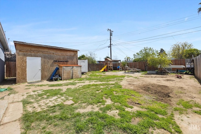 view of yard featuring an outbuilding, a fenced backyard, a playground, and a shed