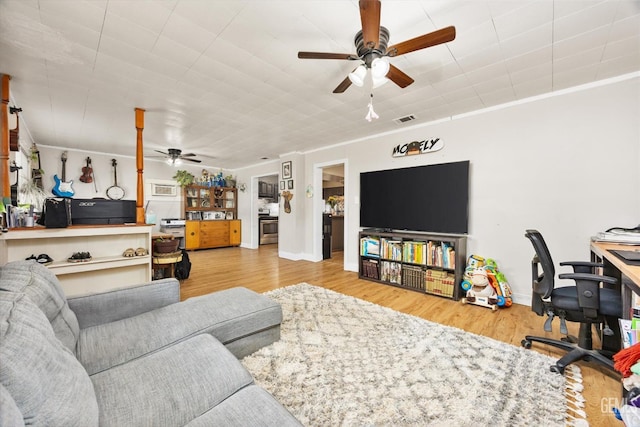living room with visible vents, ceiling fan, wood finished floors, and crown molding
