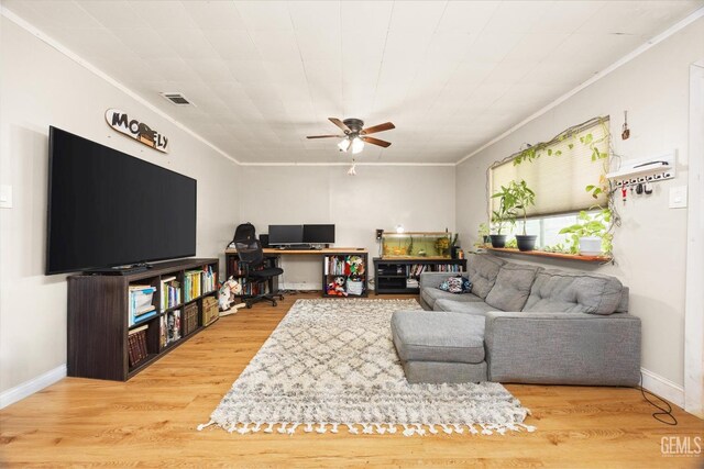 living room with crown molding, wood finished floors, baseboards, visible vents, and ceiling fan
