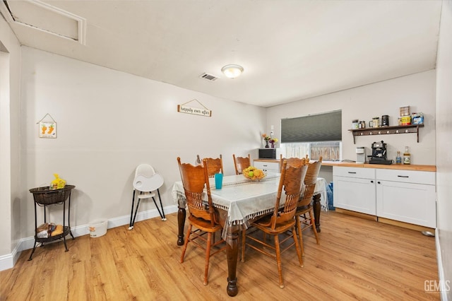 dining area featuring baseboards, light wood finished floors, and visible vents