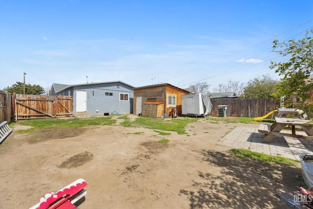 back of property with a patio, an outbuilding, a storage unit, and a fenced backyard