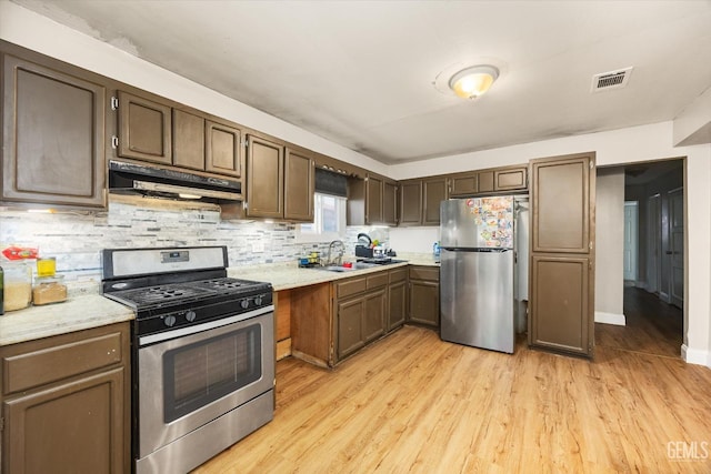 kitchen with light wood-type flooring, visible vents, under cabinet range hood, and appliances with stainless steel finishes