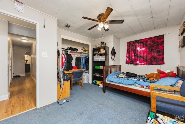 carpeted bedroom with visible vents, a closet, and a ceiling fan