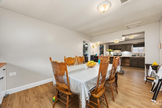 dining area with baseboards, visible vents, light wood-style floors, and attic access