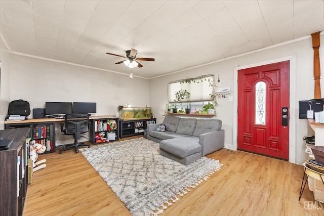 living area with light wood finished floors, crown molding, and a ceiling fan