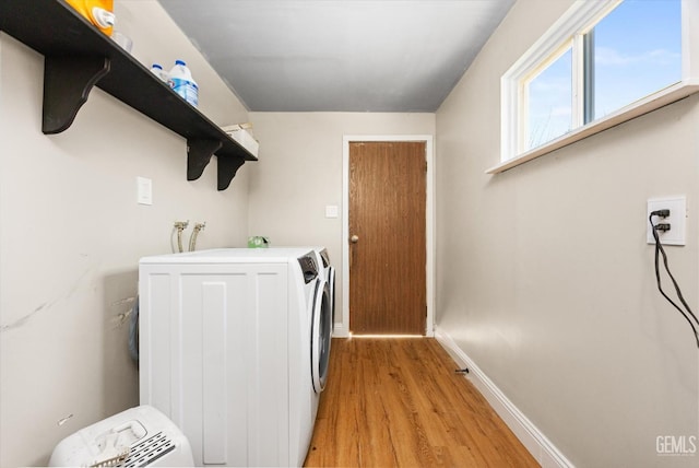 washroom featuring baseboards, washing machine and dryer, laundry area, and light wood finished floors