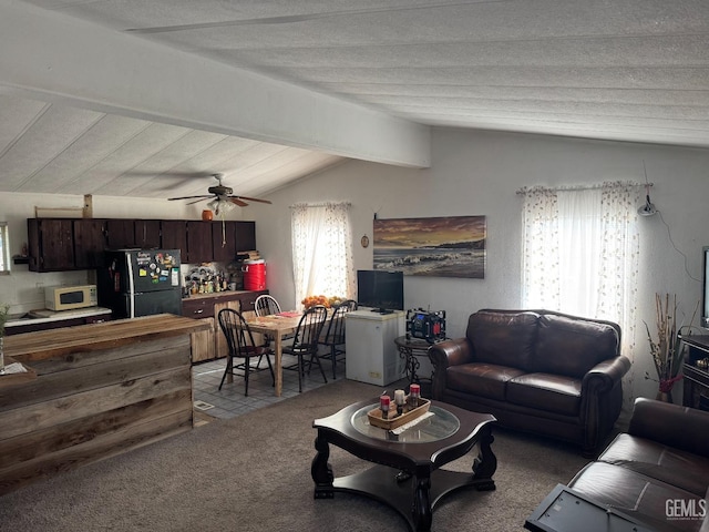 carpeted living area with vaulted ceiling with beams, ceiling fan, and a textured ceiling