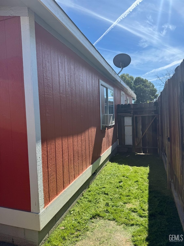 view of side of home with fence and a yard