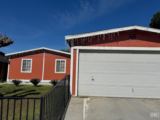 garage with fence and concrete driveway