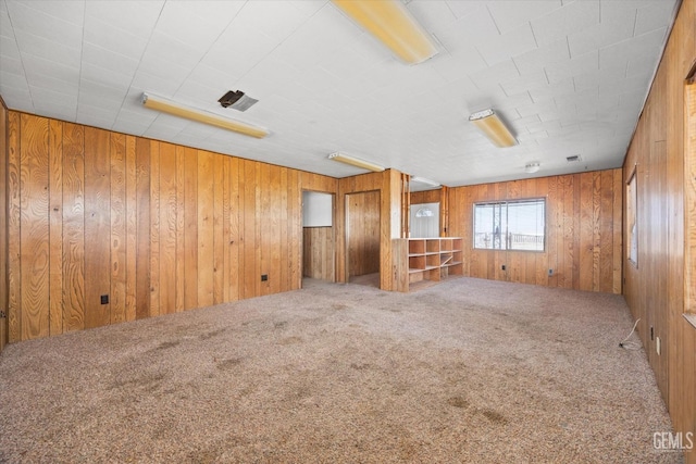 empty room featuring wooden walls and carpet flooring
