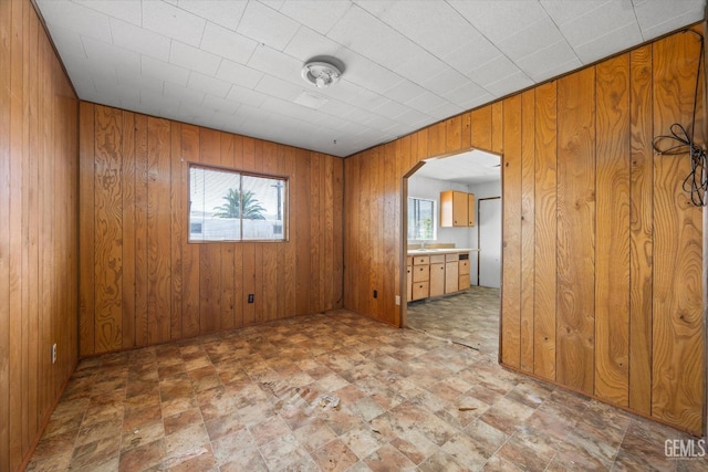 unfurnished room with arched walkways and wooden walls