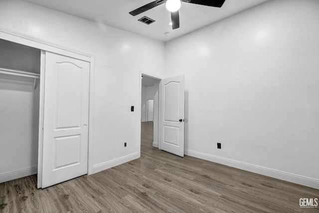 unfurnished bedroom featuring hardwood / wood-style flooring, a closet, and ceiling fan