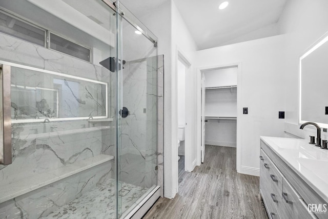 bathroom with an enclosed shower, vanity, wood-type flooring, and lofted ceiling