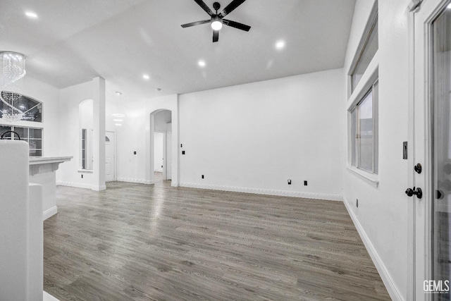 unfurnished living room with ceiling fan with notable chandelier and wood-type flooring