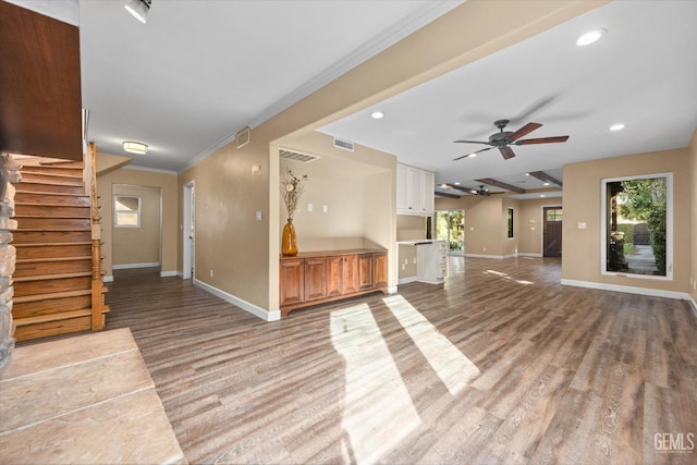 unfurnished living room featuring ornamental molding, ceiling fan, and light wood-type flooring