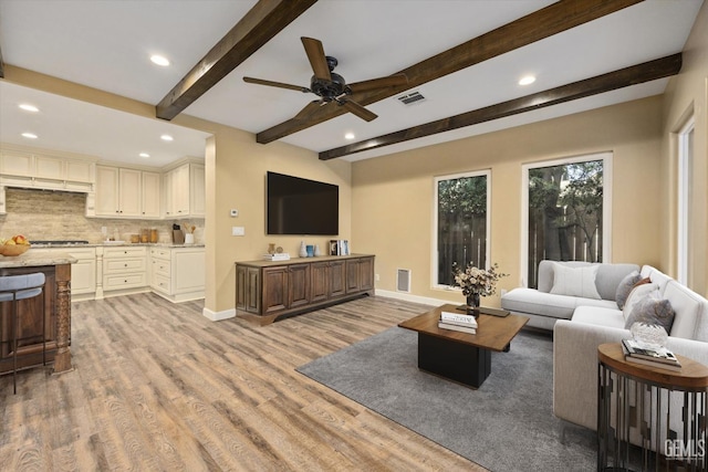 living room with ceiling fan, beam ceiling, and light hardwood / wood-style flooring