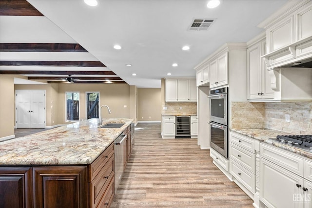 kitchen featuring white cabinetry, light stone countertops, sink, and a large island