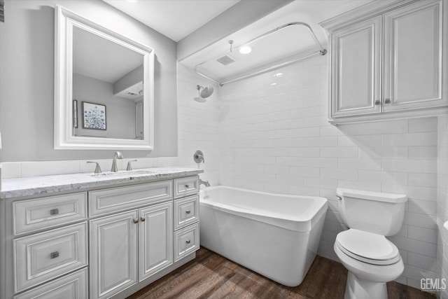 full bathroom with tiled shower / bath, wood-type flooring, tile walls, vanity, and toilet