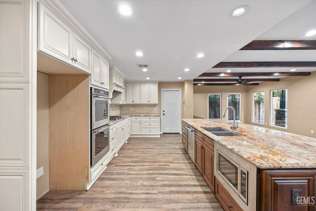 kitchen with white cabinetry, sink, light stone counters, and stainless steel appliances