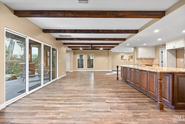 kitchen featuring light stone countertops, a large island, a wealth of natural light, and light wood-type flooring