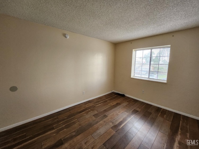 5913 El Camino Ave, Bakersfield, CA 93313 - unfurnished room featuring dark wood-type flooring, a textured ceiling, and baseboards