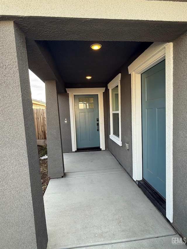 entrance to property featuring a patio area, fence, and stucco siding