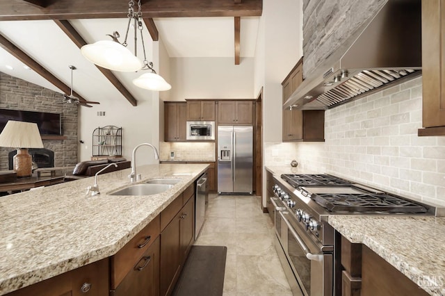 kitchen with wall chimney range hood, stainless steel appliances, open floor plan, a ceiling fan, and tasteful backsplash