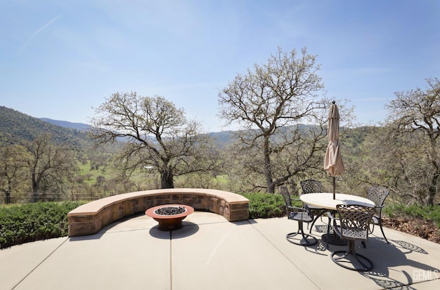 view of patio / terrace with a mountain view, outdoor dining space, and a wooded view