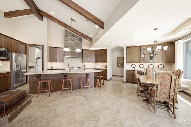 kitchen with appliances with stainless steel finishes, a breakfast bar area, a chandelier, a large island, and decorative backsplash
