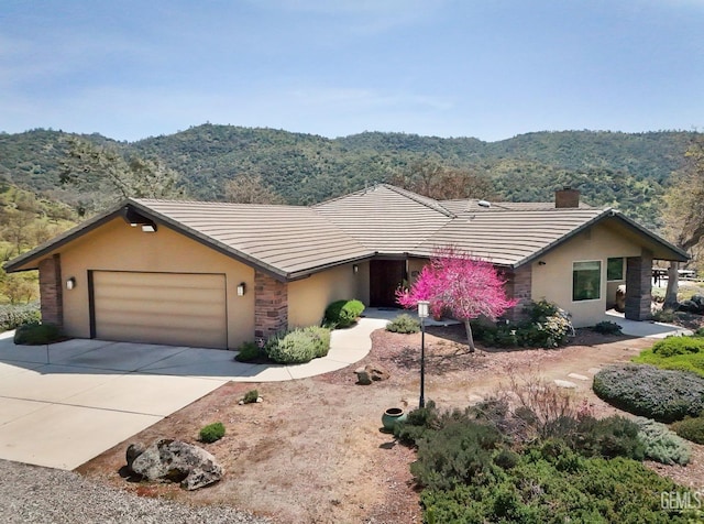 single story home with a mountain view, a chimney, a tile roof, and stucco siding