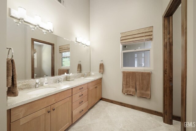 full bath featuring double vanity, baseboards, visible vents, and a sink