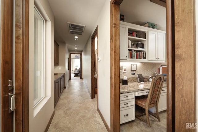 corridor featuring baseboards, visible vents, and light tile patterned floors