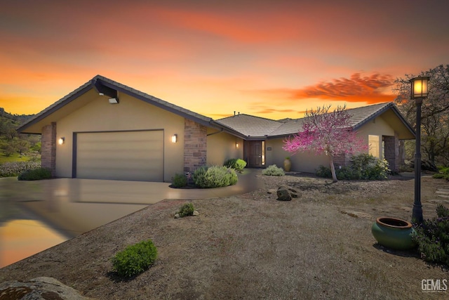 ranch-style house featuring concrete driveway, an attached garage, a tile roof, and stucco siding