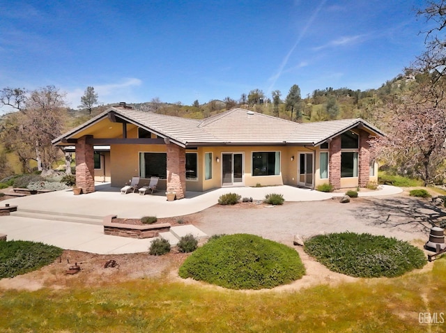 rear view of house featuring a tiled roof, a patio area, and stucco siding