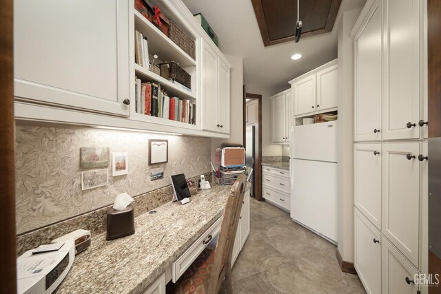 kitchen featuring white cabinets, light stone countertops, open shelves, freestanding refrigerator, and stainless steel dishwasher