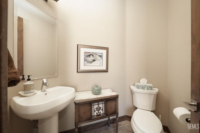 half bath featuring a sink, tile patterned floors, and toilet