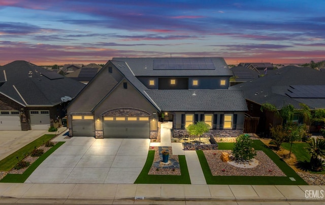 14822 Plumeria Ct, Bakersfield, CA 93314 - view of front facade featuring an attached garage, roof mounted solar panels, driveway, stucco siding, and stone siding