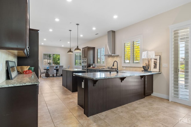 14822 Plumeria Ct, Bakersfield, CA 93314 - kitchen featuring wall chimney exhaust hood, a center island, a peninsula, light stone countertops, and recessed lighting