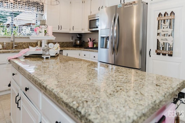 7116 Jolynn St, Bakersfield, CA 93308 - kitchen with appliances with stainless steel finishes, a sink, white cabinetry, and light stone counters