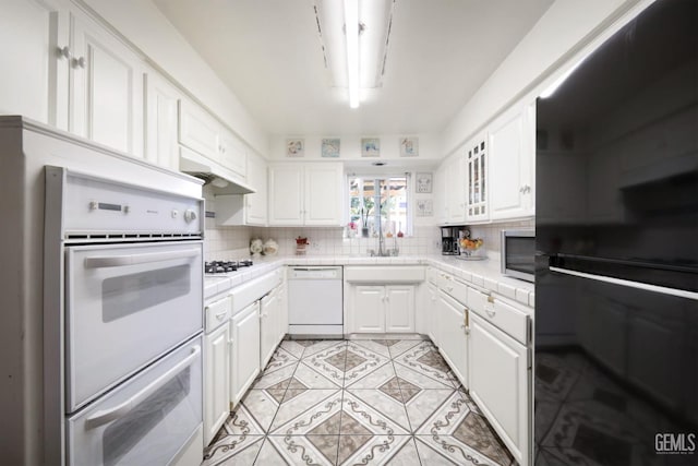 kitchen with white appliances, white cabinetry, sink, and decorative backsplash