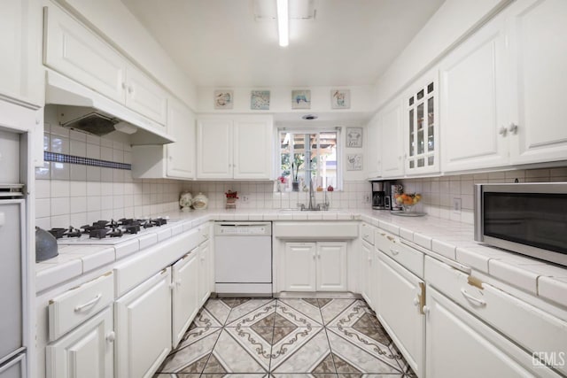 kitchen featuring white appliances, tasteful backsplash, tile counters, white cabinets, and sink