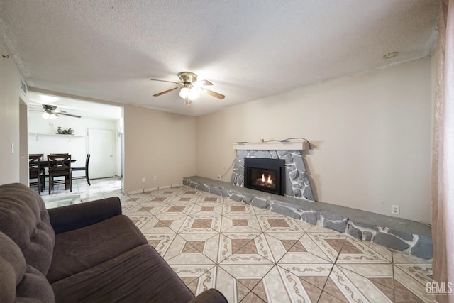 living room with a textured ceiling, ceiling fan, and a fireplace