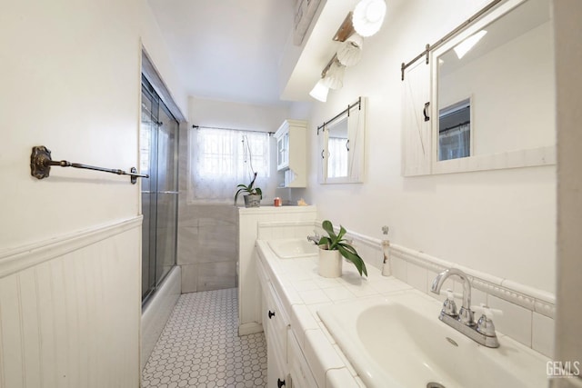 bathroom with tile patterned floors, shower / bath combination with glass door, and vanity