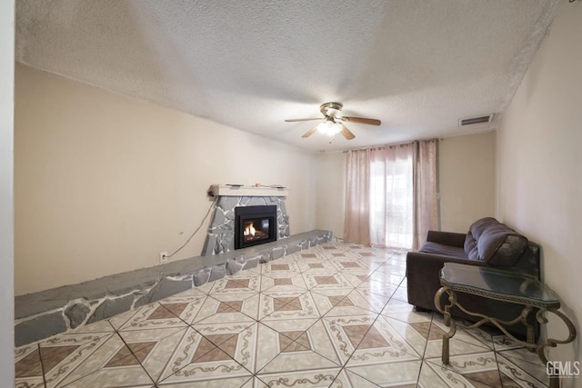 tiled living room with a premium fireplace, a textured ceiling, and ceiling fan