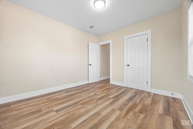 unfurnished bedroom featuring light wood-type flooring, baseboards, and visible vents