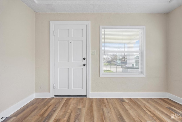 foyer with a textured ceiling, baseboards, and wood finished floors