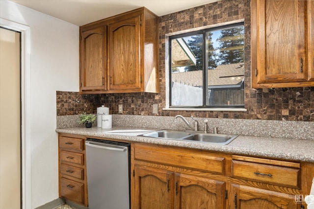 kitchen featuring a sink, backsplash, stainless steel dishwasher, and light countertops