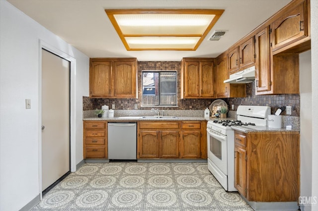 kitchen with under cabinet range hood, white range with gas cooktop, brown cabinets, and dishwasher